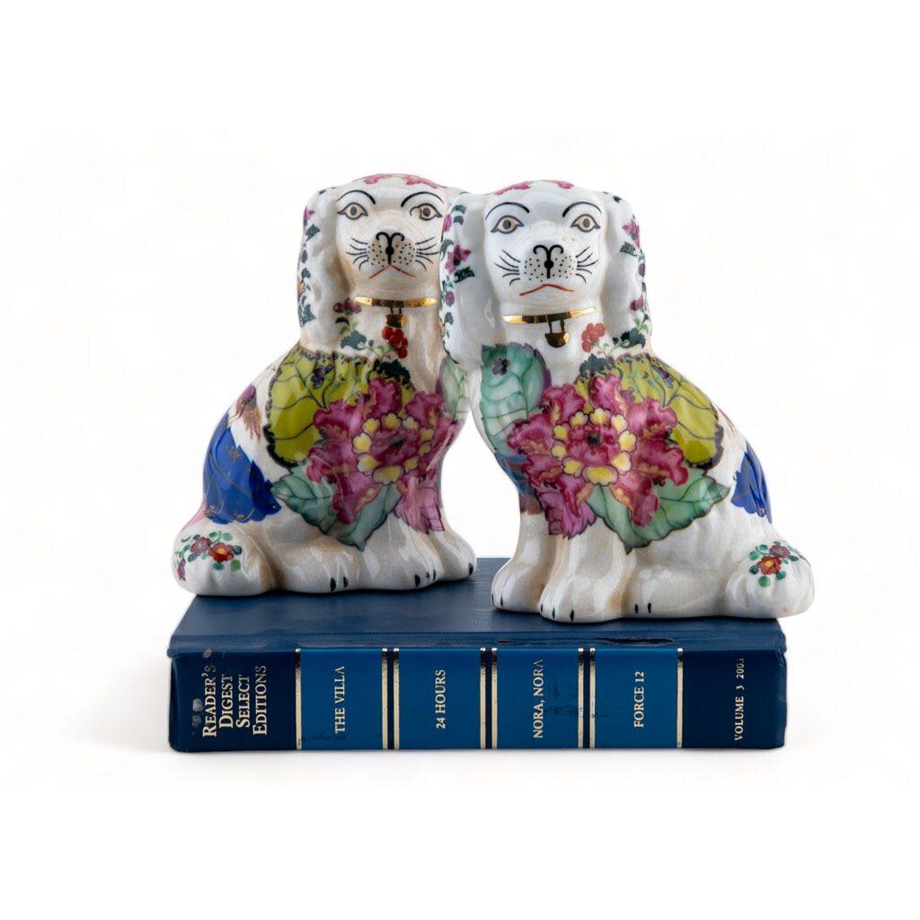 Pair of ceramic dogs in tobacco leaf pattern with pink, green, blue and gold.
